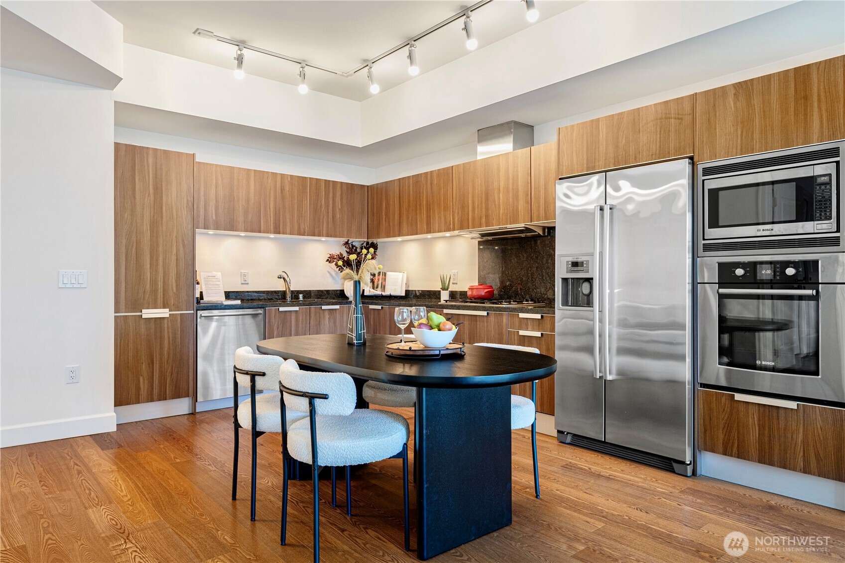 1920 4th Avenue, Unit 1809 Seattle, WA 98101 - Photo 8 of 30 a kitchen with granite countertop a refrigerator a stove a sink dishwasher a dining table and chairs with wooden floor