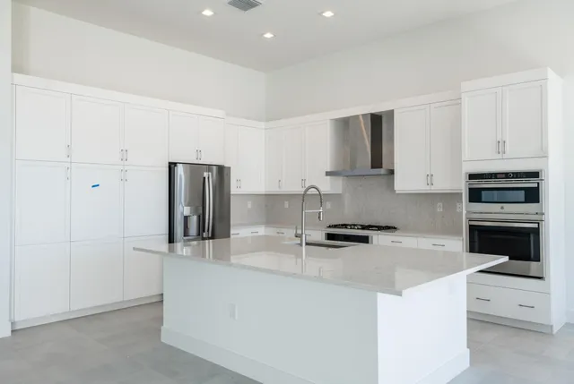 a kitchen with granite countertop a refrigerator stove and sink