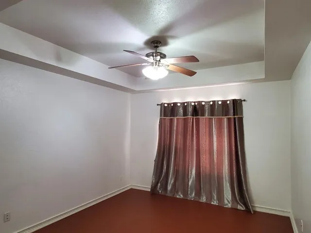 an empty room with a ceiling fan and carpet
