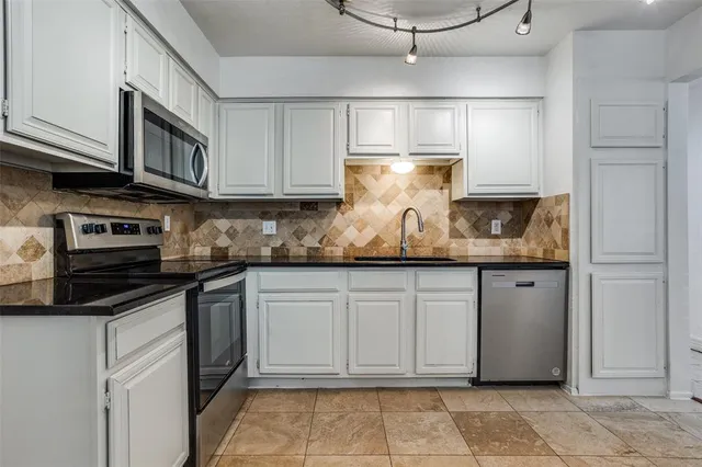 a kitchen with stainless steel appliances granite countertop a sink stove and cabinets