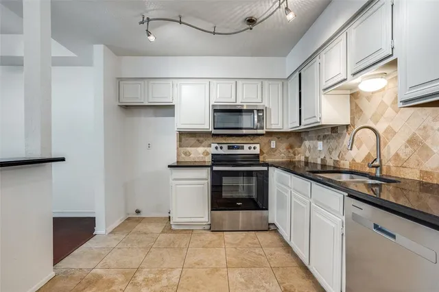 a kitchen with kitchen island granite countertop a sink stainless steel appliances and cabinets