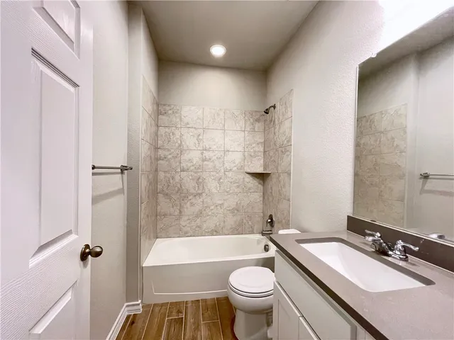 a bathroom with a sink a toilet a mirror a bathtub and shower