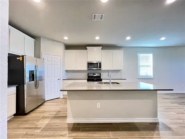 a large kitchen with stainless steel appliances granite countertop a large counter top and a stove top oven