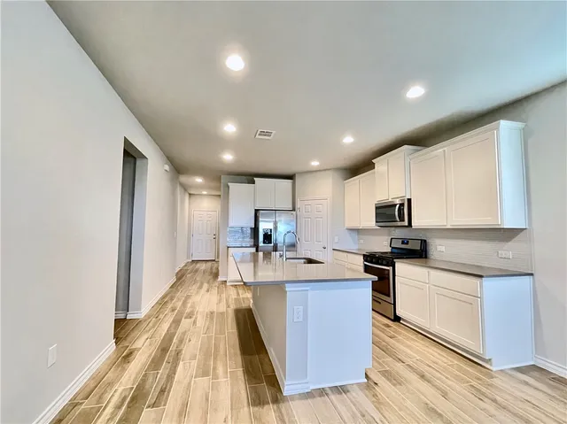 a large kitchen with kitchen island a stove a sink a refrigerator and cabinets