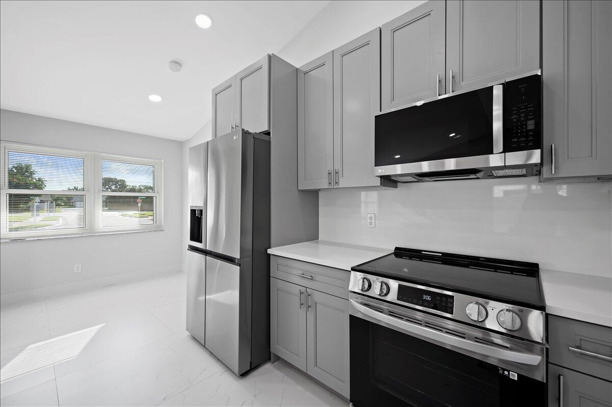 196 Raintree Trail Jupiter, FL 33458 - Photo 12 of 26 a kitchen with stainless steel appliances a stove microwave and sink