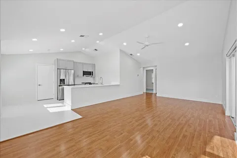 a view of kitchen with kitchen island wooden floor appliances and cabinets