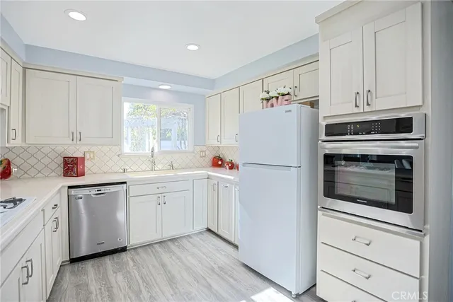 a kitchen with white cabinets white stainless steel appliances and sink