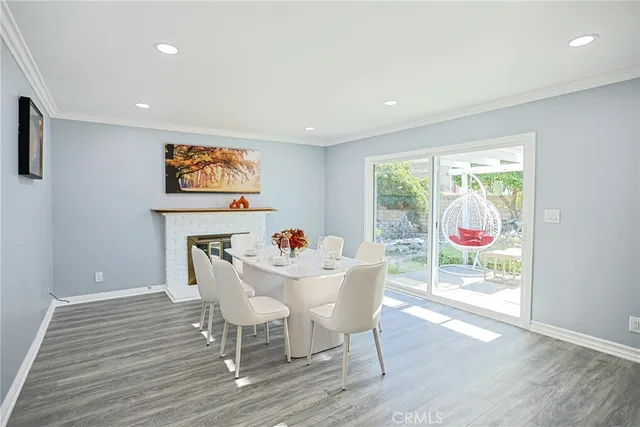 a view of a dining room with furniture one side kitchen view and wooden floor