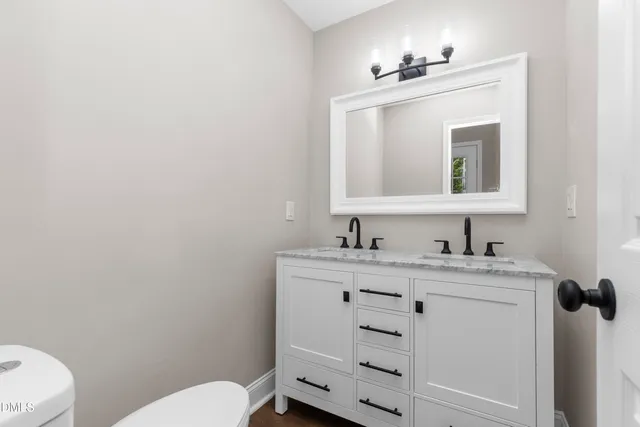 a bathroom with a toilet sink vanity and mirror
