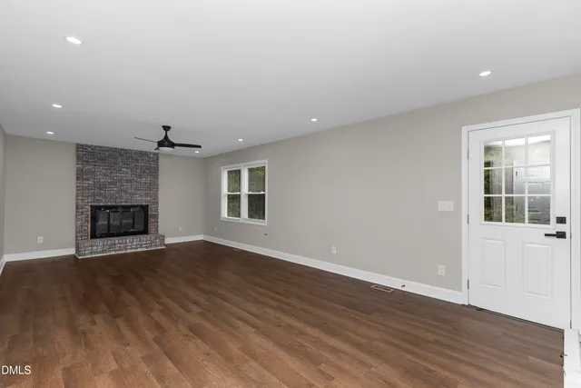 an empty room with wooden floor and a fireplace