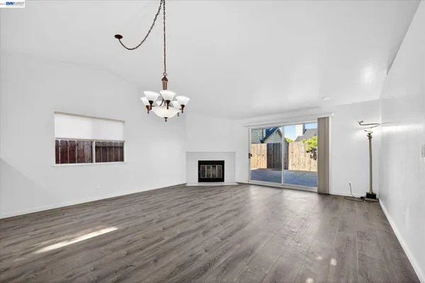 a view of a livingroom with a chandelier fan a fireplace and wooden floor