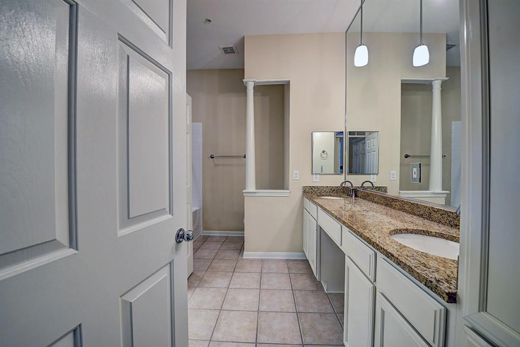 a large bathroom with a granite countertop double vanity sink and mirror