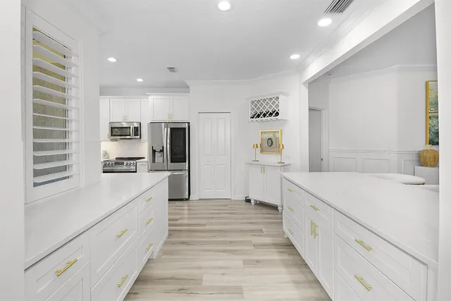 a large white kitchen with a large window a sink and a refrigerator
