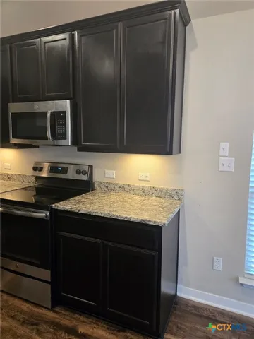 a kitchen with granite countertop wood cabinets and stainless steel appliances