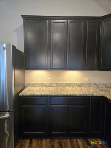 a kitchen with granite countertop wooden cabinets and refrigerator