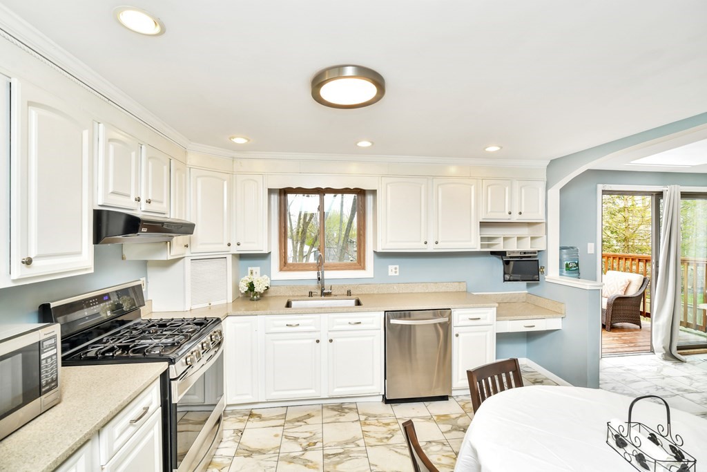 15 Old Farm Road Randolph, MA 02368 - Photo 2 of 22 a kitchen with a sink stove and white cabinets with wooden floor