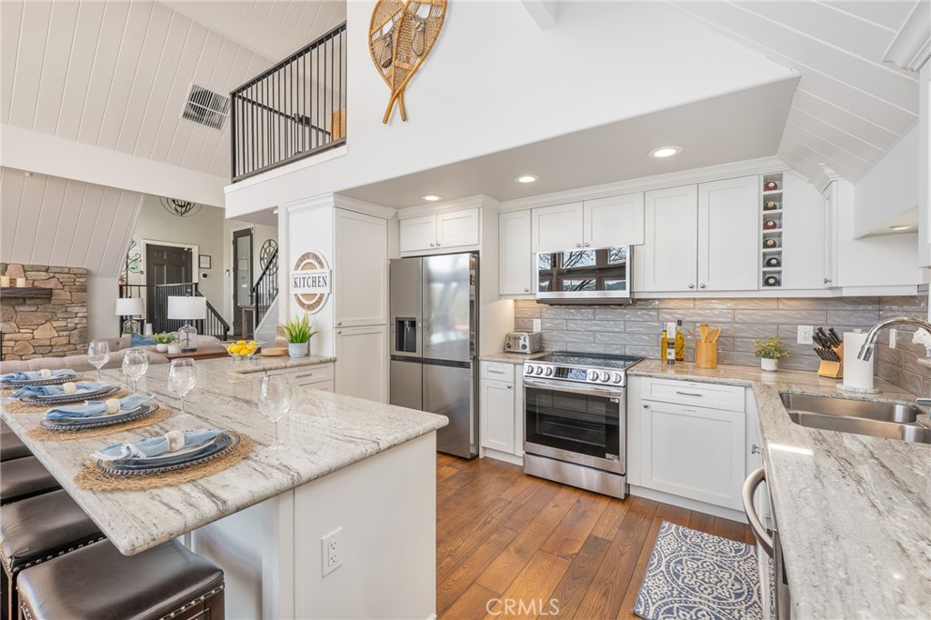27550 North Bay Road Lake Arrowhead, CA 92352 - Photo 17 of 53 a kitchen with stainless steel appliances granite countertop a refrigerator a stove a sink a dining table and chairs with wooden floor