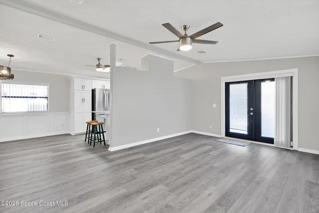 an empty room with wooden floor fan and windows