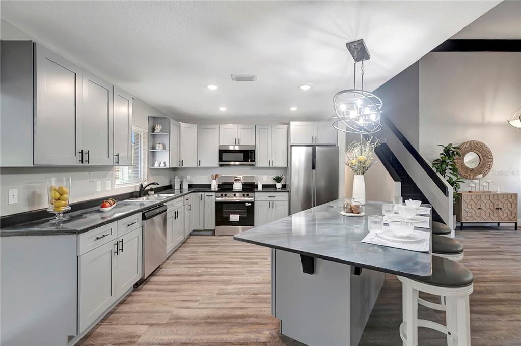 16133 Ravendale Drive Tampa, FL 33618 - Photo 13 of 46 a kitchen with stainless steel appliances kitchen island granite countertop a sink a stove and chairs