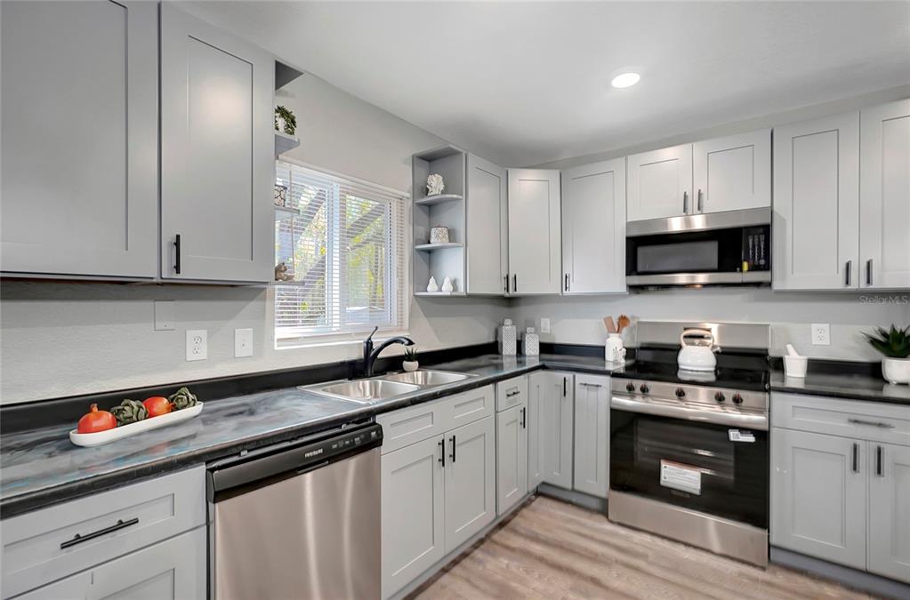 16133 Ravendale Drive Tampa, FL 33618 - Photo 16 of 46 a kitchen with stainless steel appliances granite countertop a sink a stove and a microwave