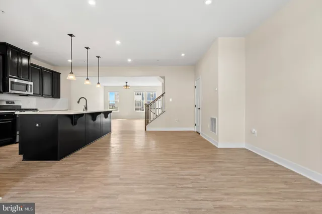 a kitchen with stainless steel appliances kitchen island granite countertop a refrigerator a stove and a wooden floors