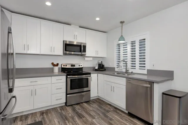 a kitchen with stainless steel appliances granite countertop a sink and cabinets with wooden floor