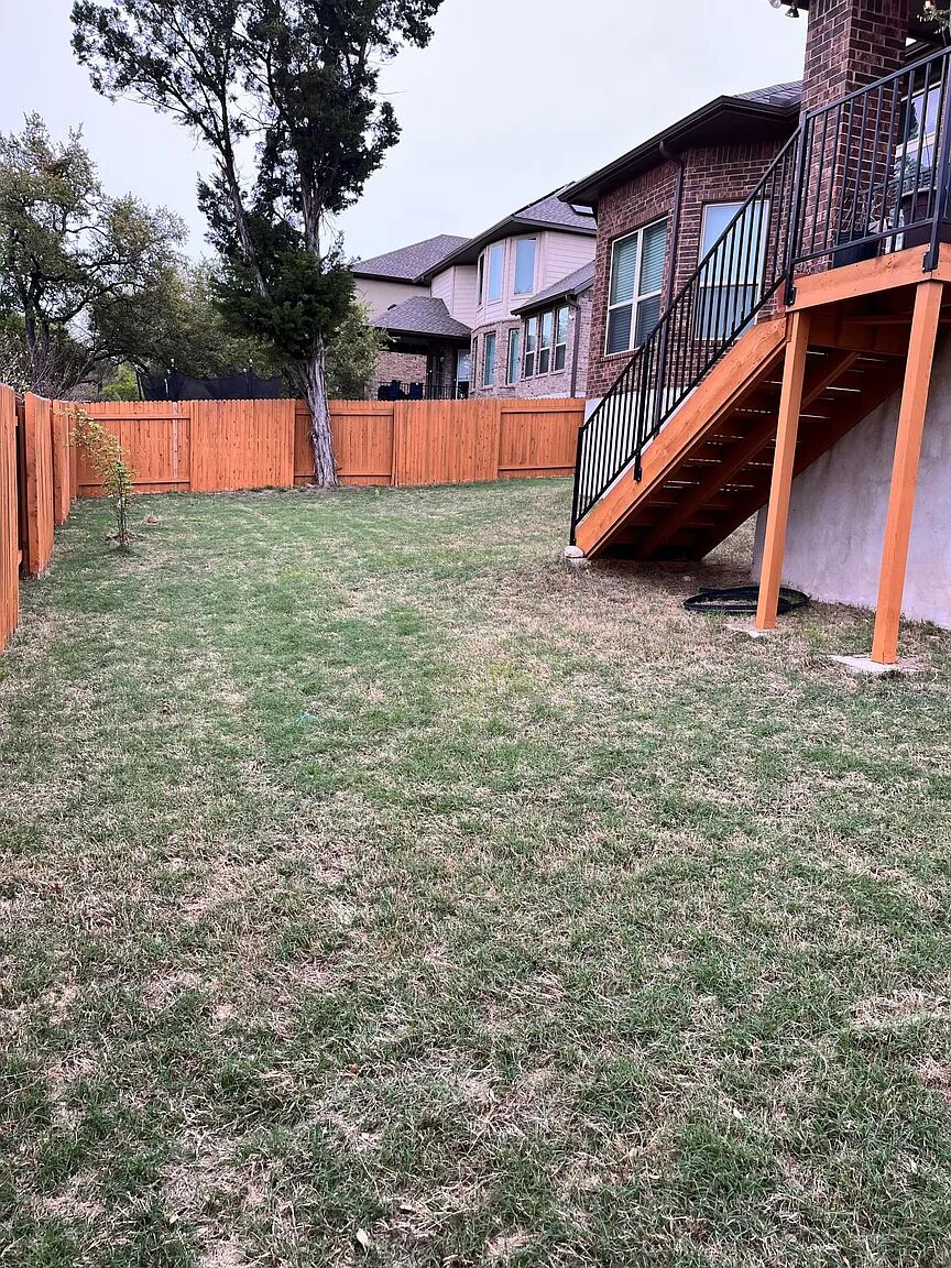 4221 Borho Ranch Street Leander, TX 78641 - Photo 14 of 16 The property features a fenced yard with a lawn, a tree, and a wooden deck with black metal railings and stairs