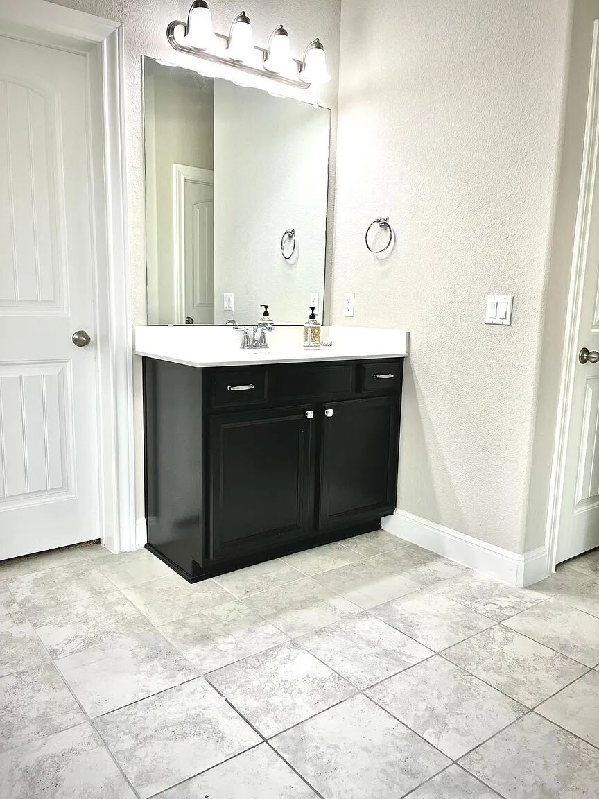 4221 Borho Ranch Street Leander, TX 78641 - Photo 7 of 16 Bathroom featuring a dark vanity with a white countertop, a large mirror, and tiled flooring