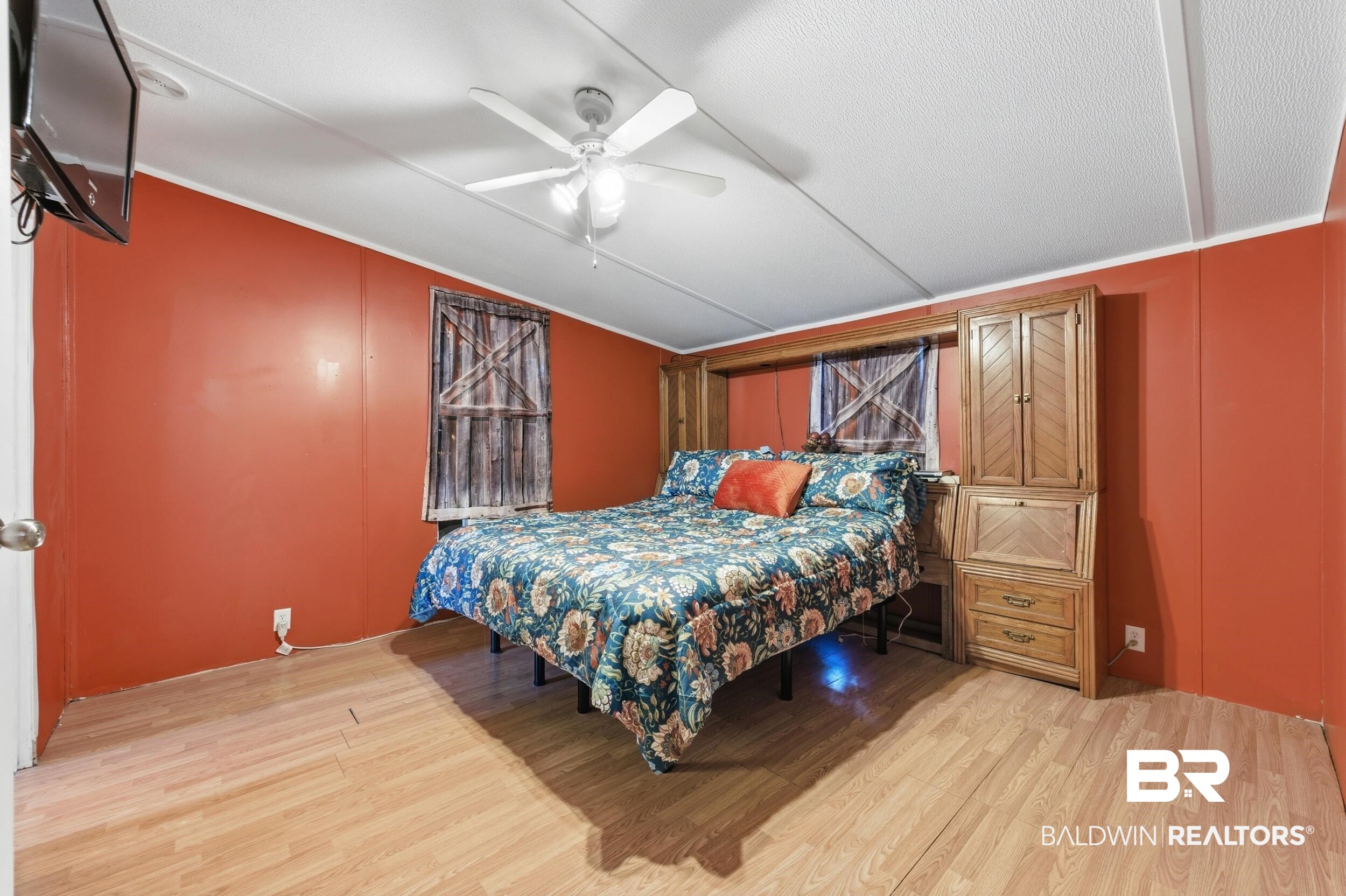 926 Tumbling Lane Atmore, AL 36502 - Photo 27 of 56 Bedroom featuring wood-finish flooring, a ceiling fan with light fixture, and built-in wood cabinetry