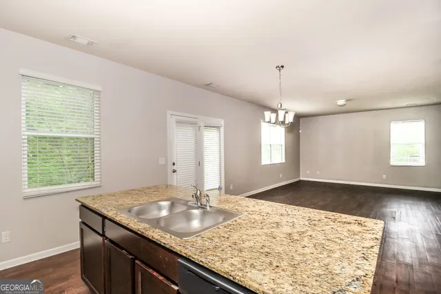 a kitchen with a sink granite counter tops and a wooden floor