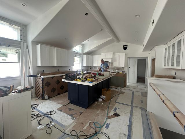 a large white kitchen with kitchen island a sink a counter space and stainless steel appliances