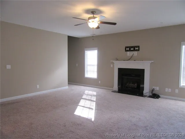 a view of a room with a fireplace chandelier fan and windows