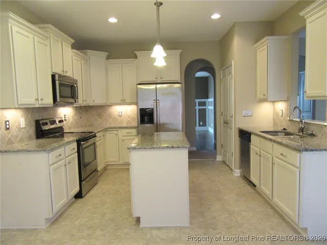 a kitchen with kitchen island granite countertop a stove top oven a sink dishwasher a dining table and chairs with wooden floor