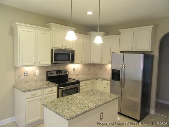 a kitchen with granite countertop a refrigerator a sink a stove a microwave and island