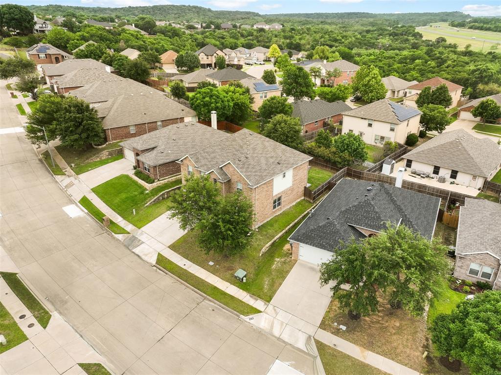 6522 Portside Ridge Lane Dallas, TX 75249 - Photo 31 of 37 Residential streetscape with paved roadways and sidewalks, featuring brick-clad and light-sided homes, mature trees, and manicured lawns