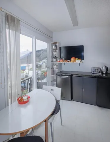 a living room with a table chairs and a refrigerator