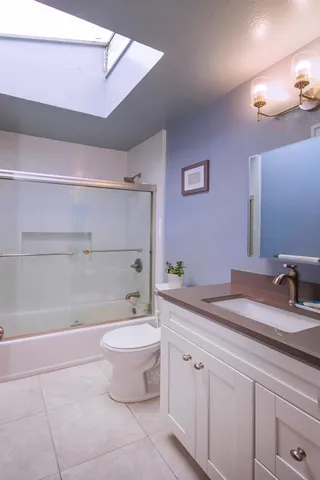 a bathroom with a granite countertop sink a toilet and a mirror