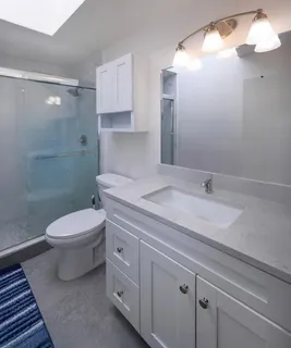 a bathroom with a granite countertop sink a toilet and shower