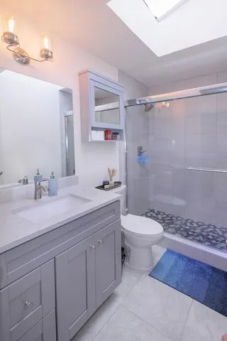a bathroom with a granite countertop sink toilet a mirror and shower