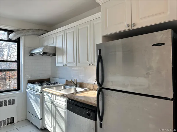 a kitchen with stainless steel appliances granite countertop a refrigerator a sink and white cabinets