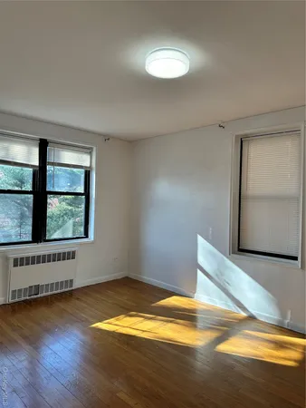 a view of an empty room with window and wooden floor