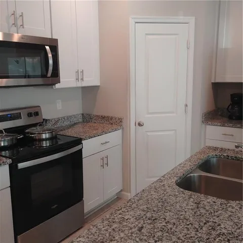 a kitchen with granite countertop white cabinets and black appliances