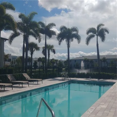 a view of a swimming pool with a patio and palm trees
