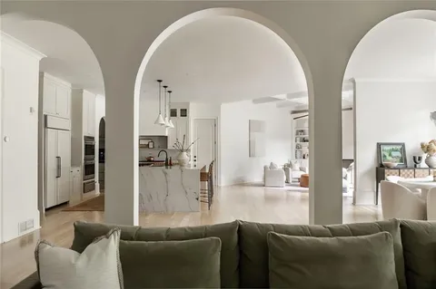 a kitchen with kitchen island granite countertop a refrigerator a stove a oven and white cabinets with wooden floor