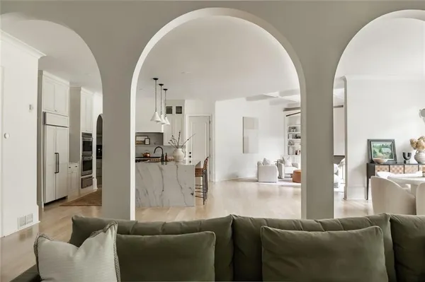 a kitchen with kitchen island granite countertop a refrigerator a stove a oven and white cabinets with wooden floor