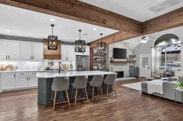 a kitchen with a sink dishwasher a dining table and chairs with wooden floor