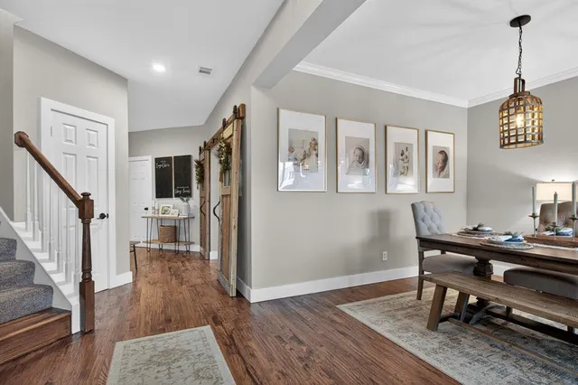 a dining room with wooden floor a chandelier a wooden table and chairs