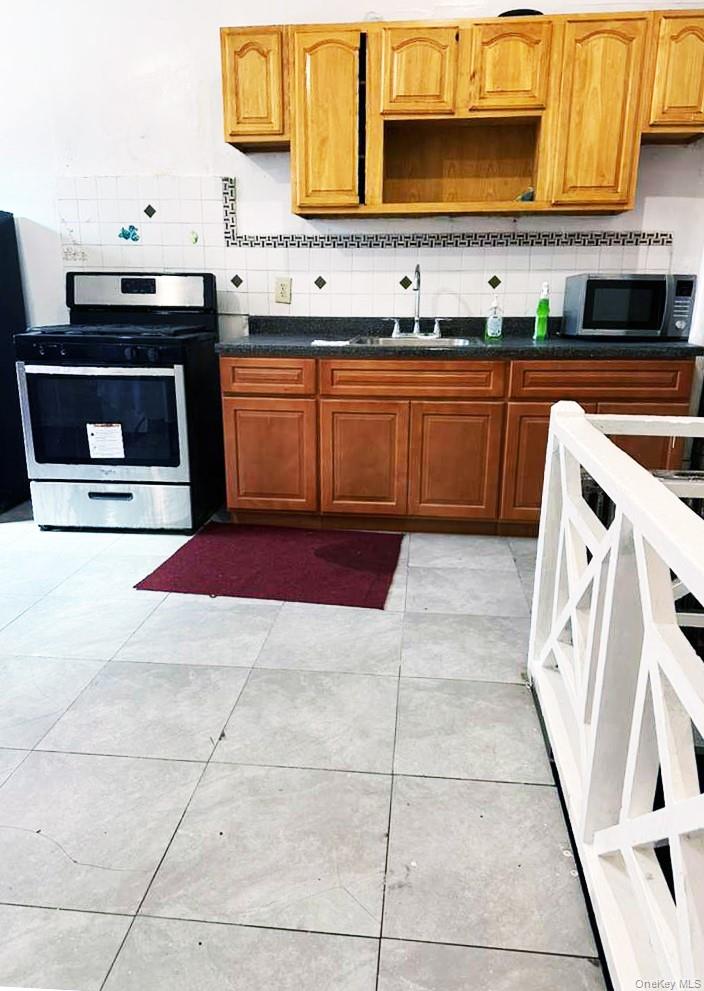 88-22 85th Street Queens, NY 11421 - Photo 38 of 39 a kitchen with stainless steel appliances granite countertop a stove a sink and a microwave