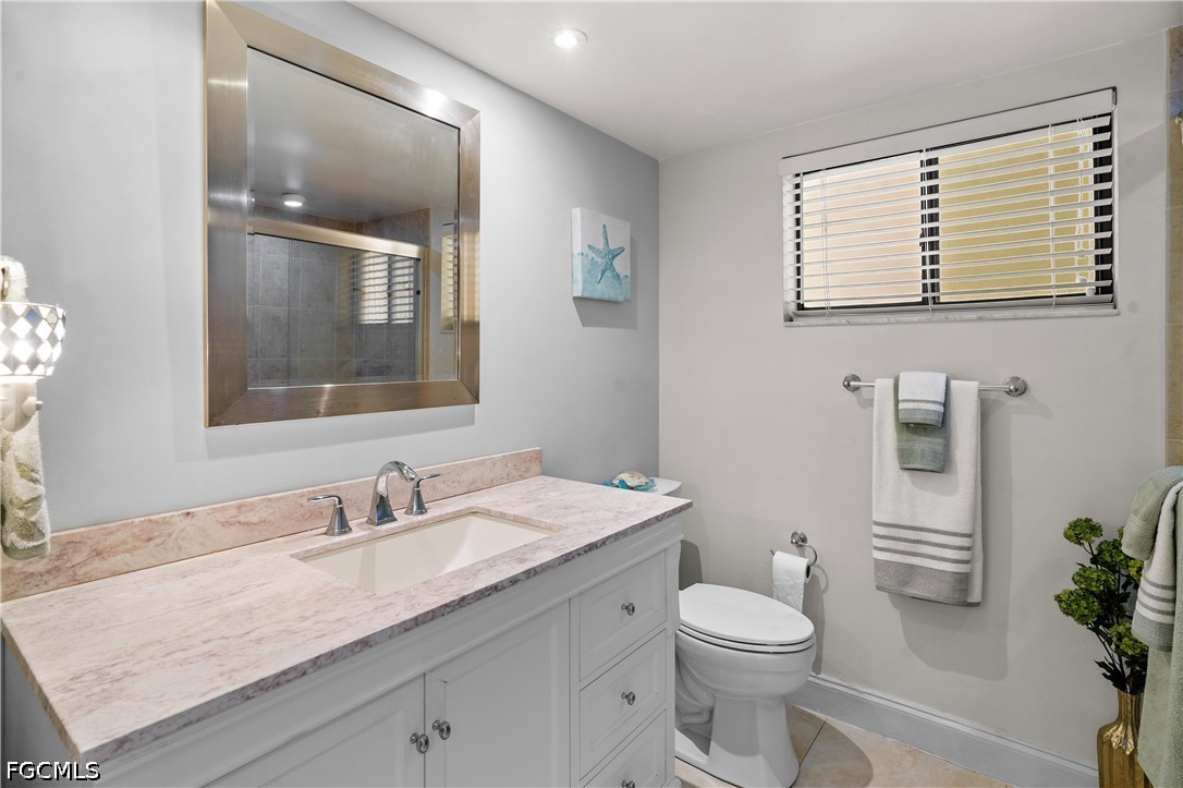 413 Augusta Boulevard, Unit 105 Naples, FL 34113 - Photo 27 of 45 a bathroom with a granite countertop sink toilet and mirror