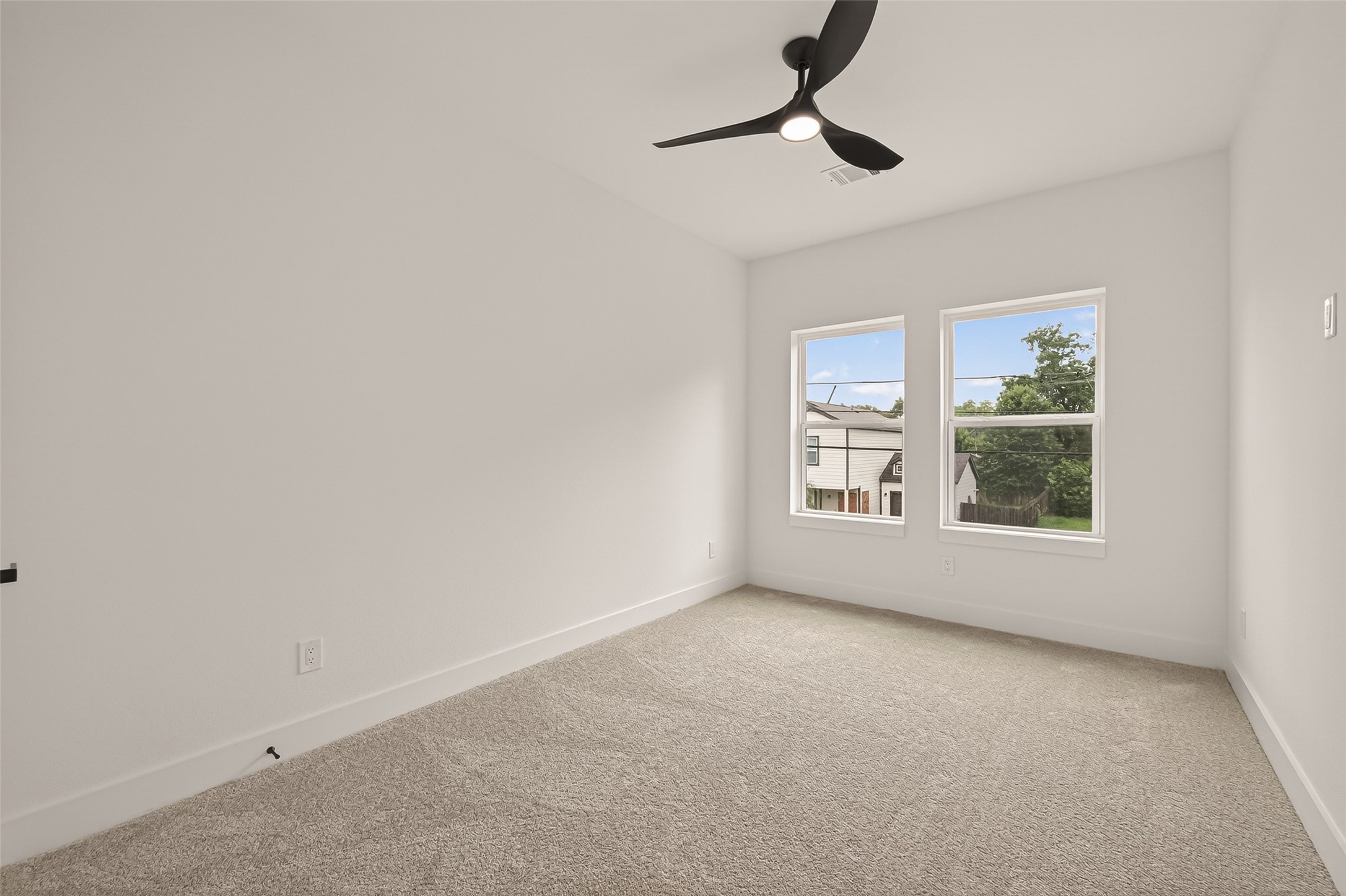 6808 Madrid Street Houston, TX 77021 - Photo 21 of 31 This bright bedroom features neutral carpeting, fresh white walls, and two large windows that offer ample natural light. A modern ceiling fan adds a stylish touch.